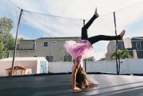 Girl upside down doing handstand on trampoline — Stock Photo