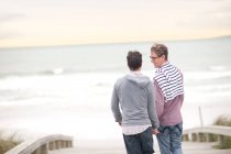 Pareja gay charlando en la playa - foto de stock