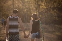 Молодая пара, идущая по лесу, держась за руки — стоковое фото