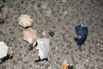 Vista aérea de personas con paraguas en el pavimento - foto de stock