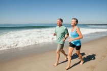 Seniorpaar joggt am Strand — Stockfoto