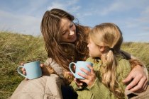 Mother and daughter outdoors with drinks — Stock Photo