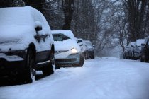 Автомобили, припаркованные на снежной улице — стоковое фото