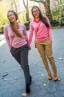 Twin sisters holding hands, walking on street — Stock Photo