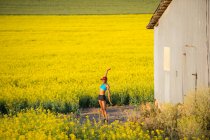Young woman runner stretching in field of oil seed rape — Stock Photo