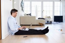 Мужчина сидит на полу и использует ноутбук — стоковое фото
