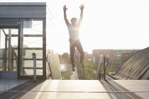 Man training, jumping mid air on footbridge — Stock Photo
