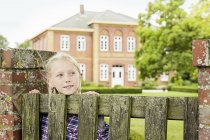 Girl by wooden gate, looking away — Stock Photo