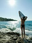 Jovem mulher tirando t-shirt junto ao mar — Fotografia de Stock