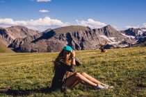 Woman sitting in field with moose, Rocky Mountain National Park, Colorado, USA — Stock Photo