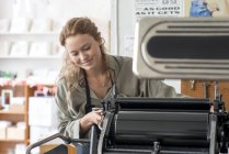Female printer preparing printing machine in workshop — Stock Photo