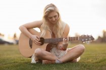 Donna che suona la chitarra in erba — Foto stock