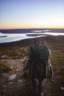 Back view of hiker walking with backpack near lake in keimiotunturi, finland — Stock Photo