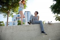Jovem casal sentado na parede ao ar livre — Fotografia de Stock