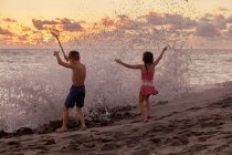 Família feliz se divertindo na praia ao pôr do sol — Fotografia de Stock