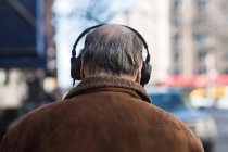 Visão traseira do homem idoso usando fones de ouvido — Fotografia de Stock