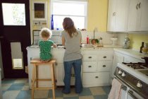 Mother and child at kitchen sink — Stock Photo