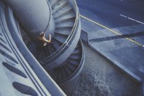Jovem mulher correndo escada espiral ao ar livre — Fotografia de Stock