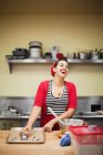 Young baker laughing while preparing food — Stock Photo