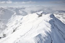 Catena montuosa innevata con nuvole nebbiose — Foto stock