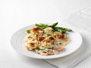 Plate of salmon dauphinoise with asparagus — Stock Photo