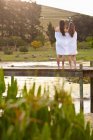 Дві молоді жінки, що стоять на річковому пірсі, загорнуті в ковдру — стокове фото