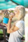Woman smelling plant in nursery — Stock Photo