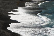 Surfen am schwarzen Lavastrand — Stockfoto