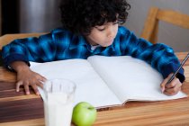 Хлопчик робить домашнє завдання за столом — стокове фото