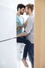 Мужская пара на кухне, лицом к лицу, обнимаются — стоковое фото