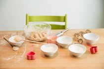 Pastella in ciotola, mestolo, stampi da forno sul tavolo — Foto stock