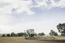 Farmer and teenage grandson waving whilst ploughing with tractor — Stock Photo