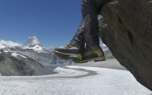 Hombre sentado en la roca por el Matterhorn, Zermatt, Canton Wallis, Suiza - foto de stock