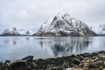 Küste und schneebedeckte Berge, die sich im Wasser spiegeln — Stockfoto