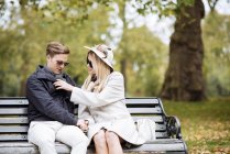 Stilvolles junges Paar sitzt auf Parkbank — Stockfoto