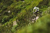 Mountain biker riding down steep hill path — Stock Photo