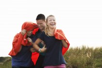 Три підлітки, загорнуті в ковдру на пляжі — стокове фото