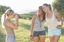 Three young female friends posing for photographs — Stock Photo