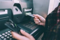 Женская рука вставляет кредитную карту в банкомат — стоковое фото