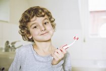 Retrato de menino no banheiro segurando escova de dentes olhando para a câmera sorrindo — Fotografia de Stock
