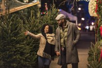 Romantic happy couple enjoying city during winter holidays looking at Christmas trees — Stock Photo