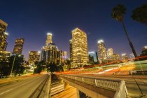 Vista de rascacielos de la ciudad y autopista por la noche, Los Ángeles, California, EE.UU. - foto de stock