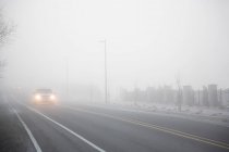 Nevoeiro em uma estrada com carro em movimento — Fotografia de Stock