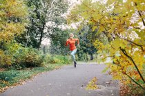 Молода жінка біжить вздовж паркової доріжки — стокове фото