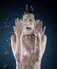 Jovem mulher espirrando água no rosto — Fotografia de Stock