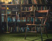 Stuhl und Lampe vor dem Bücherregal — Stockfoto
