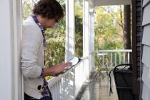 Man using tablet computer on porch — Stock Photo