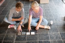 Young couple sitting on floor choosing new tiles — Stock Photo