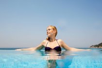 Jovem mulher na piscina infinita, olhando para longe — Fotografia de Stock