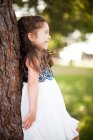 Porträt eines Mädchens, das sich lächelnd an einen Baumstamm lehnt — Stockfoto